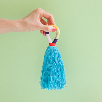 Multi-colored yarn tassels - Use them to accessorize your favorite handbag or hang them on your doorknob, so pretty! - www.yeswemadethis.com